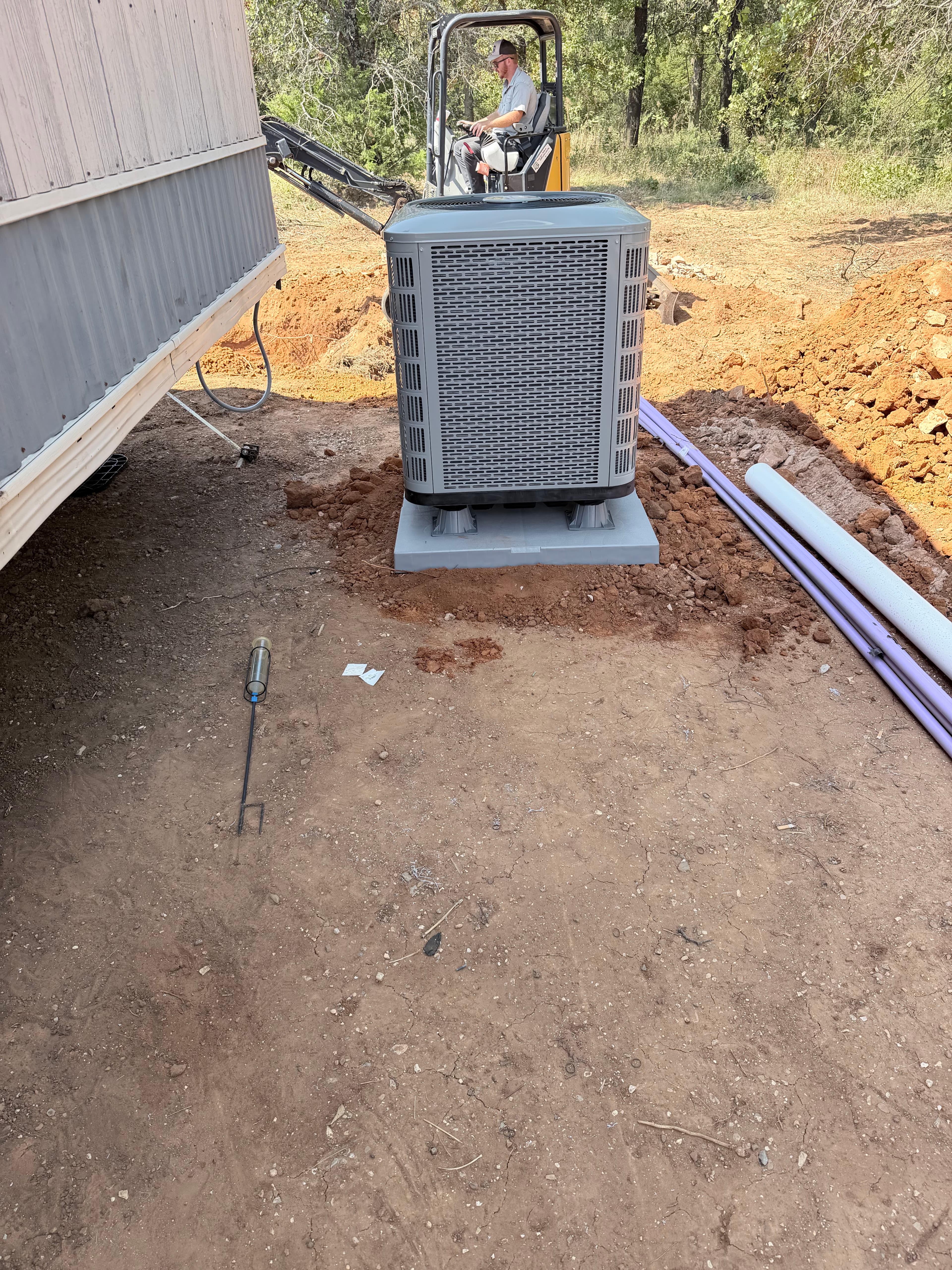 New construction install — outdoor unit set on fresh pad at job site